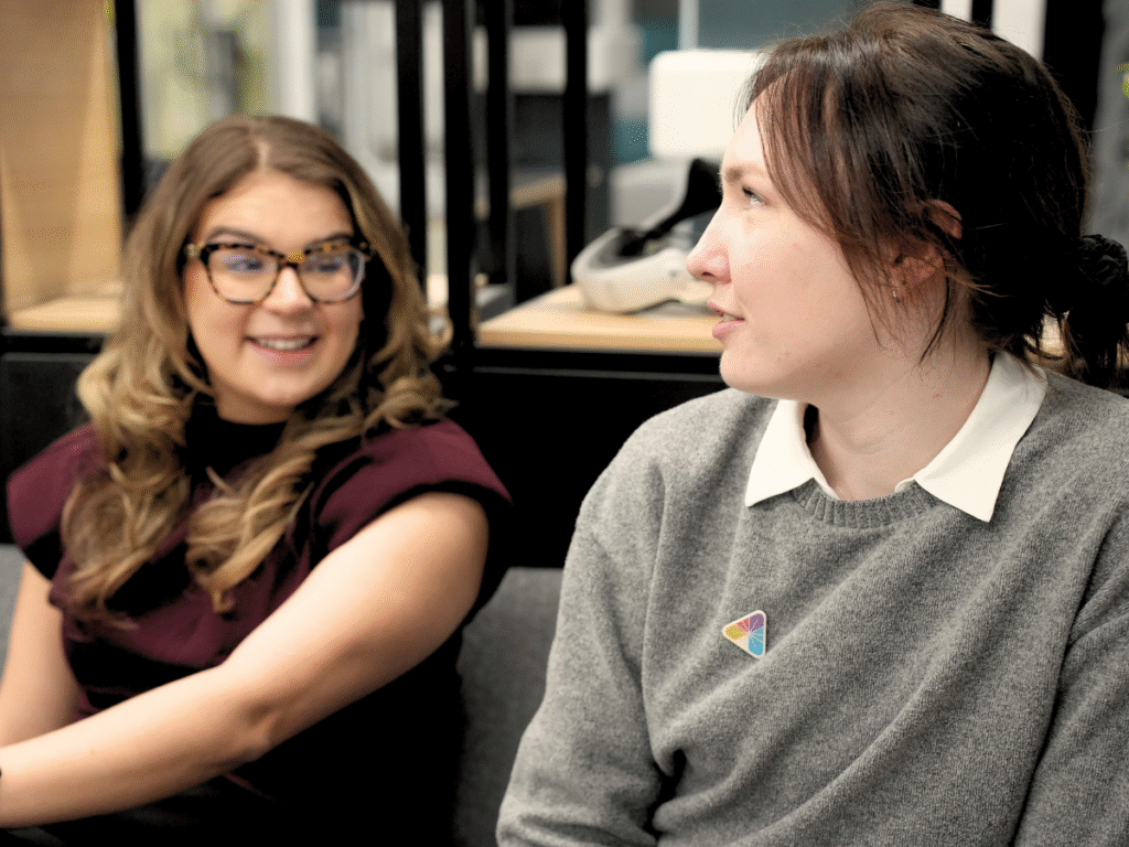 Two members of a healthcare innovation team talking together in a collaborative workspace.
